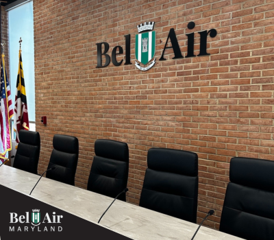 Photo of empty board chairs on the dais with Town of Bel Air logo on the wall